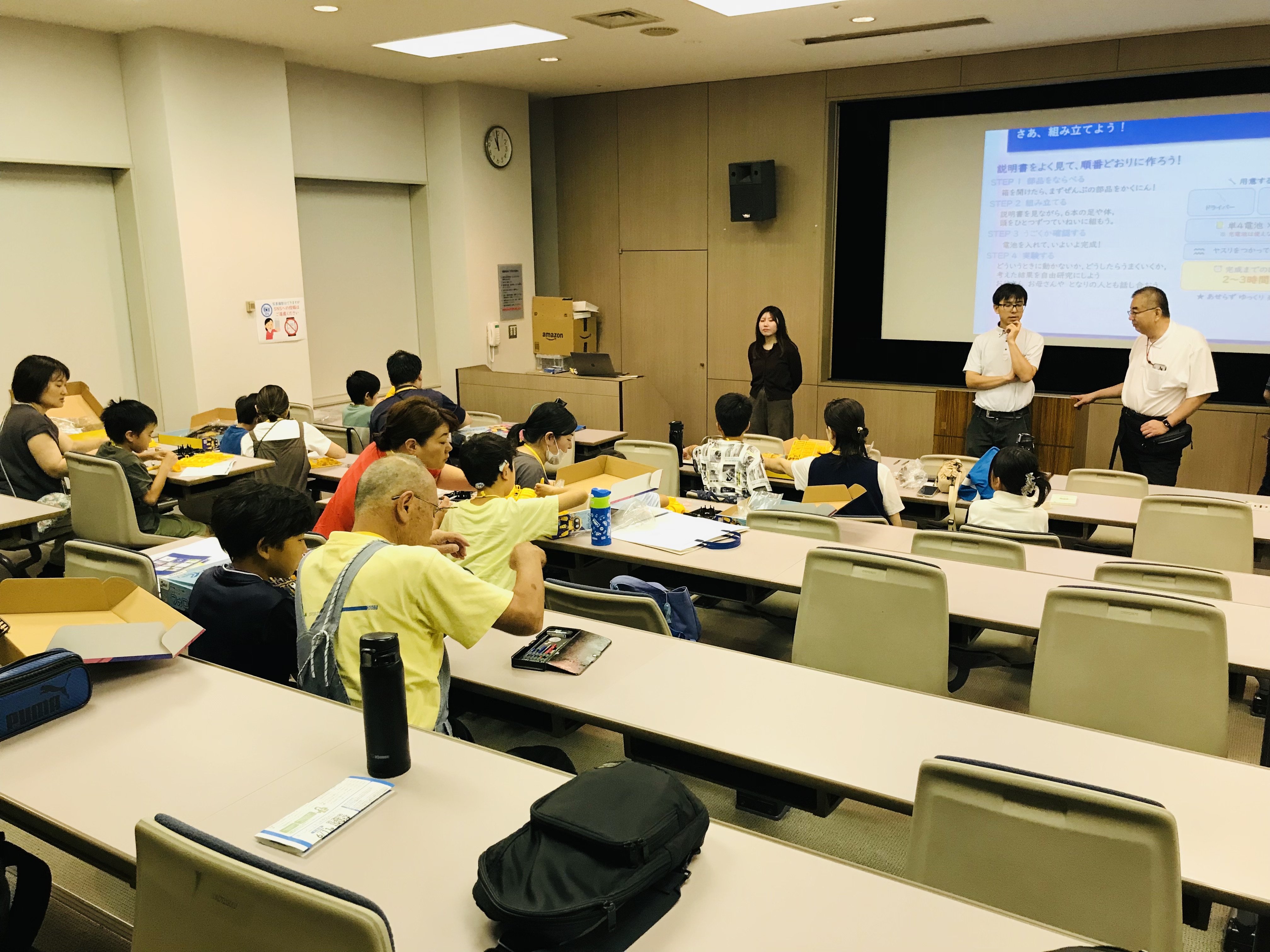 組み立て手順を説明するスライドと教室の様子