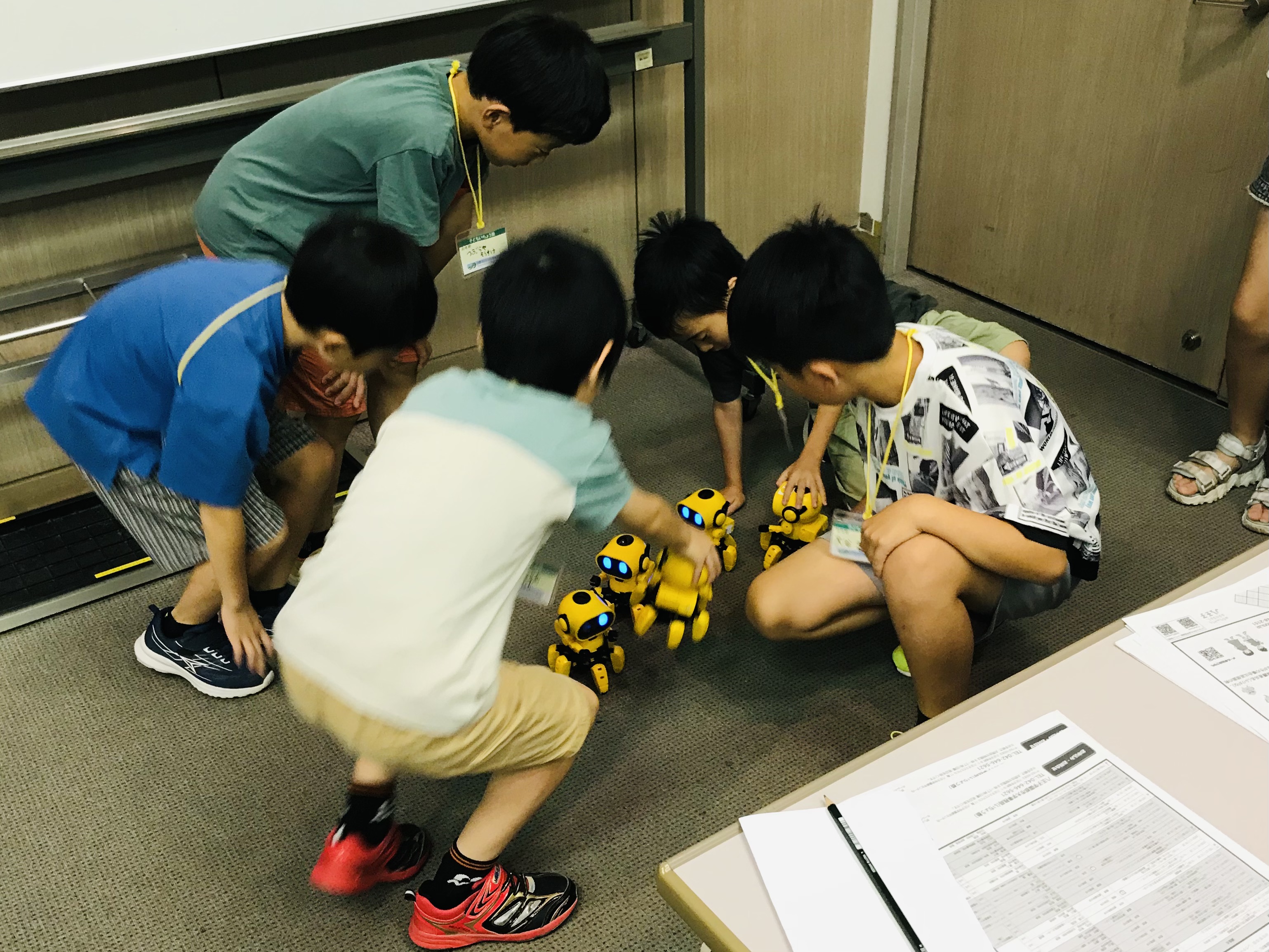 完成したロボットを床で動かして観察する子どもたち